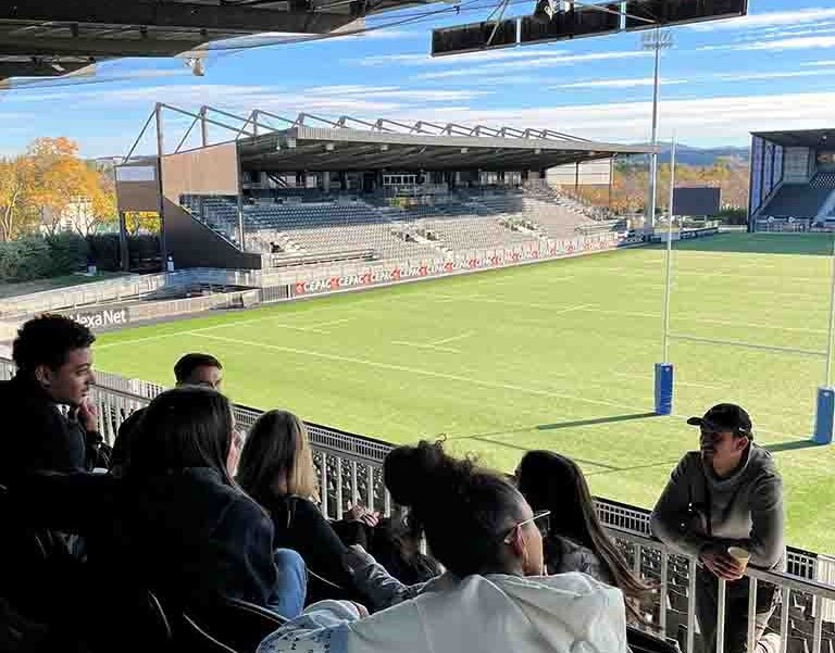 Etudiants assis dans les tribunes d'un stade de rugby